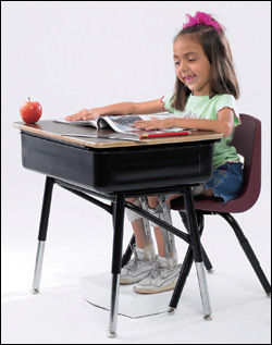 A little girl, in braces, works at her desk.