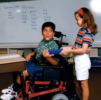 A girl hands a fellow classmate his work.