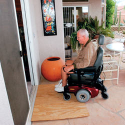 A man entering a home using a DIY plank ramp
