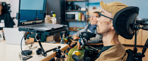 Image of a man in a wheelchair looking at a laptop screen.