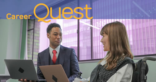 Image of two people in an office setting with laptops looking at each other.