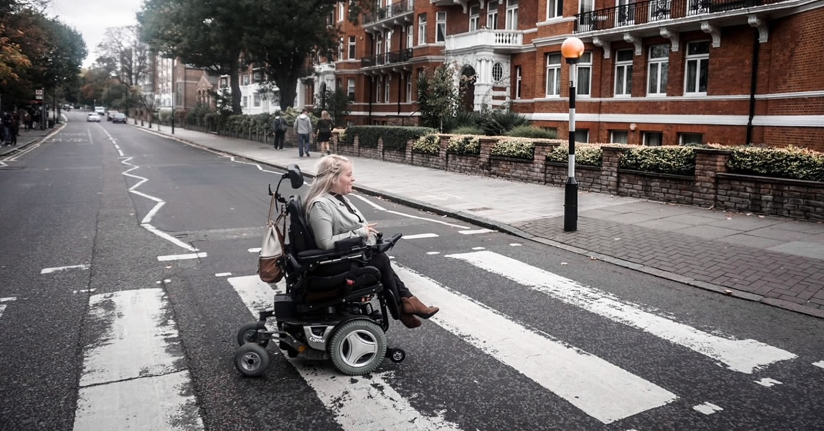 Image of a woman crossing the street in a wheelchair.